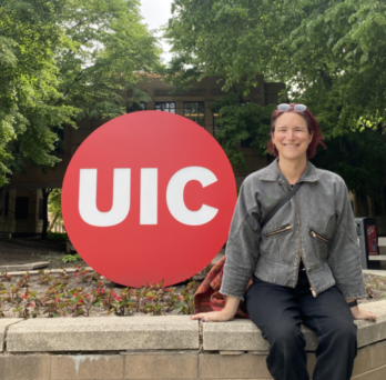 Alex Kenaith sitting by UIC Logo 